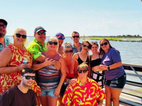 A lively group of friends poses together on a boat, enjoying a fun day out on the water — perfect for celebrations and memorable gatherings.