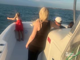 A family enjoys a boat ride on the ocean, with a child playfully reaching out over the side — a perfect moment of joy and adventure on the water.