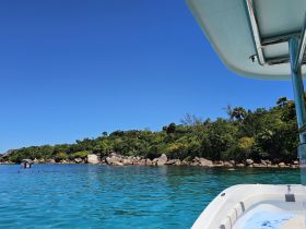 A picturesque view of a vibrant coastline with clear turquoise waters, showcasing a boat and people enjoying the beautiful scenery.