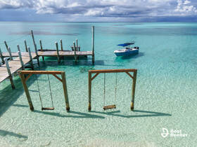 A serene view of a boat anchored near a wooden dock, surrounded by crystal-clear waters — perfect for a relaxing day on the water.