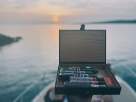 A beautifully arranged box of cigars is showcased against a stunning sunset backdrop, perfect for a relaxing evening on the water.