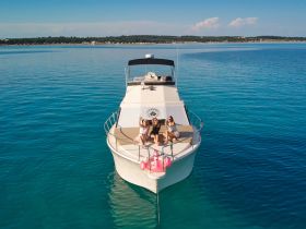 A group of friends enjoys a sunny day on the deck of a yacht, capturing the perfect moment for celebration and fun on the water.