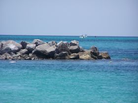 A vibrant ocean scene featuring a snorkeler near rocky outcrops, with boats in the background — a perfect snapshot of a fun day on the water.