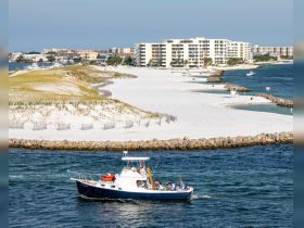 A scenic view of a boat cruising along a beautiful coastline, with white sandy beaches and a lively group onboard, perfect for showcasing coastal adventures.