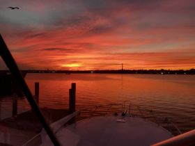 A stunning sunset view from the bow of a boat, showcasing vibrant colors reflecting on the water — perfect for serene evening cruises.