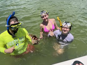 A group of snorkelers enjoys a fun day in the water, showcasing their catch while swimming in the ocean — a perfect adventure for marine enthusiasts.