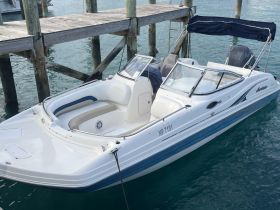 A sleek speedboat docked at a pier, showcasing its modern design and inviting seating — perfect for a day on the water.