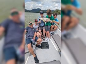 A joyful family poses on a boat, showcasing their impressive catch of the day while enjoying a fun fishing trip together.