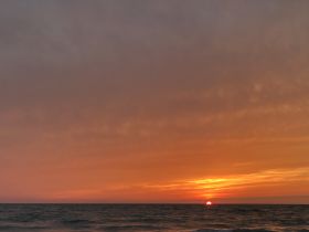 A stunning sunset over the ocean, providing a picturesque backdrop for evening boat cruises and serene moments on the water.