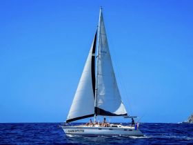 A lively group enjoys sailing on a beautiful day aboard a sleek sailboat, showcasing the joy of ocean adventures.