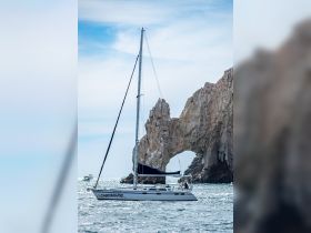 A beautiful sailboat navigates the waters near Cabo, showcasing stunning rock formations in the background — perfect for sailing enthusiasts and scenic tours.