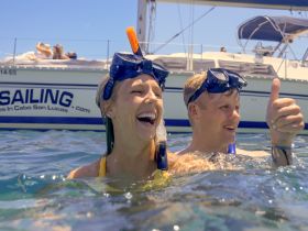 A joyful couple enjoys snorkeling in Cabo San Lucas, showcasing their excitement with a thumbs up — a perfect moment for adventure lovers.