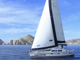 A stunning sailboat named 'Mistral' glides through the waters near Cabo San Lucas, showcasing the beauty of sailing in a picturesque coastal setting.