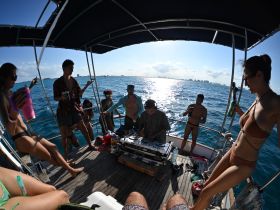 A lively group enjoys a party atmosphere on a boat, complete with music and drinks, perfect for a fun day on the water.