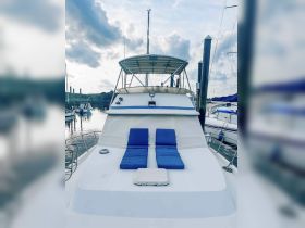 A serene view of the back deck of a yacht, featuring comfortable blue lounge cushions, perfect for relaxing at the dock.