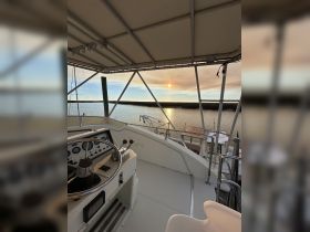 A serene view from the helm of a boat, showcasing the controls and a beautiful sunset over the water — perfect for those seeking a peaceful boating experience.