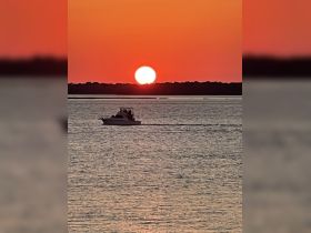 A picturesque sunset view with a boat cruising across the water, creating a serene atmosphere perfect for evening outings.