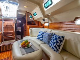 A cozy interior view of a boat cabin featuring comfortable seating and a fruit platter, perfect for relaxing during a sailing trip.