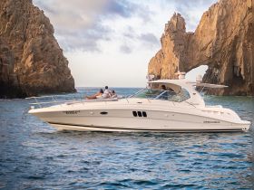 A couple relaxes on the deck of a luxurious boat near the iconic rock formations of Cabo San Lucas, creating a picturesque backdrop for romantic getaways.