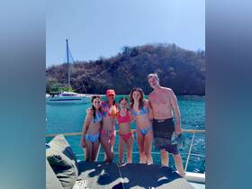 A joyful family poses together on the deck of a catamaran, enjoying a sunny day on the water — perfect for memorable beach outings and family adventures.