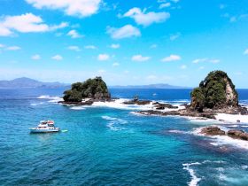 A picturesque view of a boat anchored near lush islands, showcasing the stunning coastline and vibrant turquoise waters — perfect for island hopping adventures.