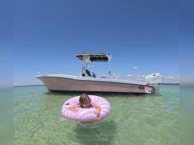 A joyful child enjoys a sunny day in the water, floating on an inflatable ring next to a sleek boat — a perfect scene for family fun and summer adventures.
