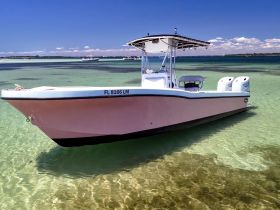 A sleek speedboat rests in shallow, clear waters, showcasing its elegant design and perfect for a day of adventure on the water.