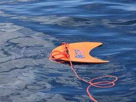 An orange floating mat is seen floating on calm blue waters, perfect for fun and relaxation during a day on the boat.
