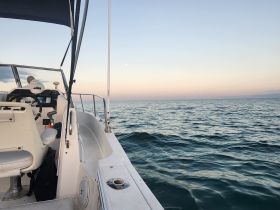 A serene view of the helm area on a boat, with a person seated in the background, perfect for capturing the essence of a peaceful boating experience at sea.