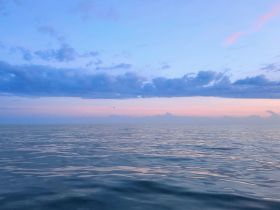A serene view of the ocean at dusk, featuring soft pastel colors in the sky and calm waters, perfect for capturing the tranquility of a boating experience.