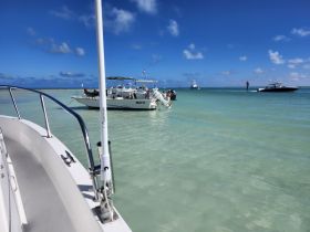 A vibrant scene of multiple boats anchored in clear waters, showcasing a lively day on the water with friends and family enjoying the sun.