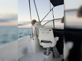 A guest enjoys the view from the helm of a boat, showcasing the comfortable seating and serene waters ahead — perfect for a relaxing day on the water.
