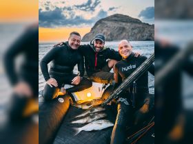 A group of friends proudly displays their catch after a successful fishing trip at sunset, showcasing camaraderie and adventure on the water.