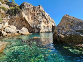 A stunning view of rocky cliffs and crystal-clear waters, showcasing the natural beauty of the coastline — perfect for exploring hidden coves and enjoying serene boat trips.