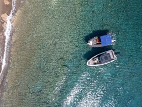 Aerial view of two speedboats anchored in crystal-clear waters, showcasing the beauty of a perfect day on the water.