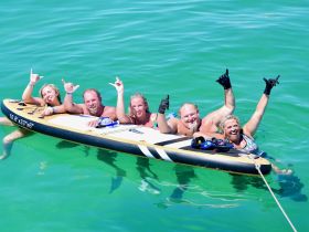 A cheerful group enjoys paddleboarding in clear turquoise waters, showcasing the fun and excitement of a perfect day on the water.