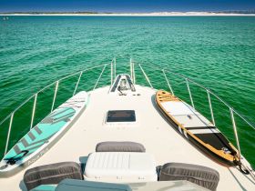 A serene view of paddleboards resting on the deck of a boat, perfect for enjoying water activities in the clear green waters.