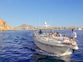 A lively group enjoys a day on the water aboard a sleek boat, showcasing the stunning coastline and perfect for memorable outings with friends.