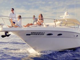 A lively group enjoys a sunny day aboard the yacht 'Breeze,' showcasing the perfect atmosphere for relaxation and celebration on the water.