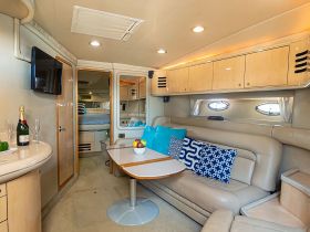 A cozy interior view of a boat's cabin featuring comfortable seating, a dining area, and elegant decor, perfect for relaxing during a day on the water.