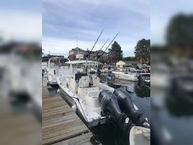 A sleek center console boat docked at the marina, equipped with fishing rods and ready for a day on the water.