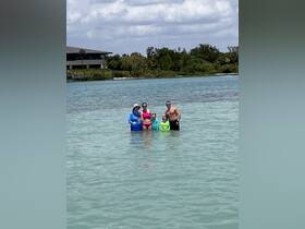 A joyful family enjoys a day at the beach, wading in shallow waters under the sun — perfect for creating lasting memories together.