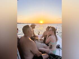A lively group enjoys a sunset boat party, capturing the perfect moment of relaxation and camaraderie on the water.