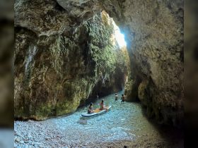 A group of friends paddleboards and enjoys swimming in a stunning cave, surrounded by breathtaking rock formations — a perfect adventure for nature lovers.