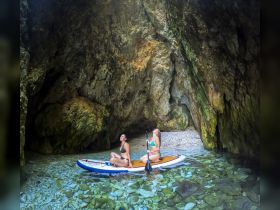 Two friends enjoy a kayaking adventure in a stunning cave, surrounded by crystal-clear waters and rocky formations — a perfect escape for thrill-seekers.