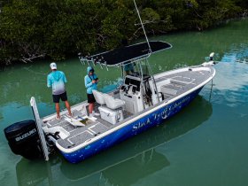 Two individuals enjoy a fishing trip on a boat, showcasing the perfect outdoor adventure on the water surrounded by lush greenery.
