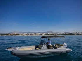 A sleek speedboat navigates the clear waters, showcasing its stylish design against a picturesque coastal backdrop.