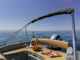 A beautifully arranged selection of fresh fruits and towels on the deck of a boat, perfect for a relaxing day on the water.