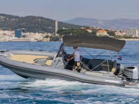 A sleek speedboat navigates through clear waters, showcasing its modern design and performance capabilities against a scenic coastal backdrop.