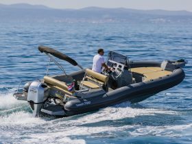 A speedboat navigates through clear waters with a captain at the helm, showcasing the thrill of boating adventures.